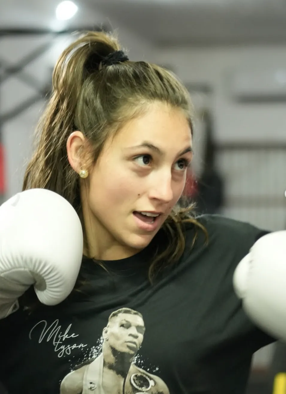 Aluna em guarda com luvas de boxe brancas