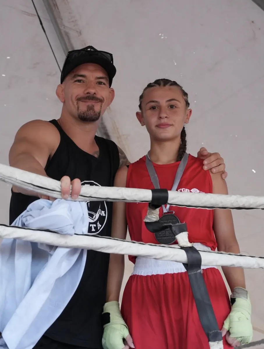 André Lopes no ringue ao lado de uma atleta de uniforme vermelho