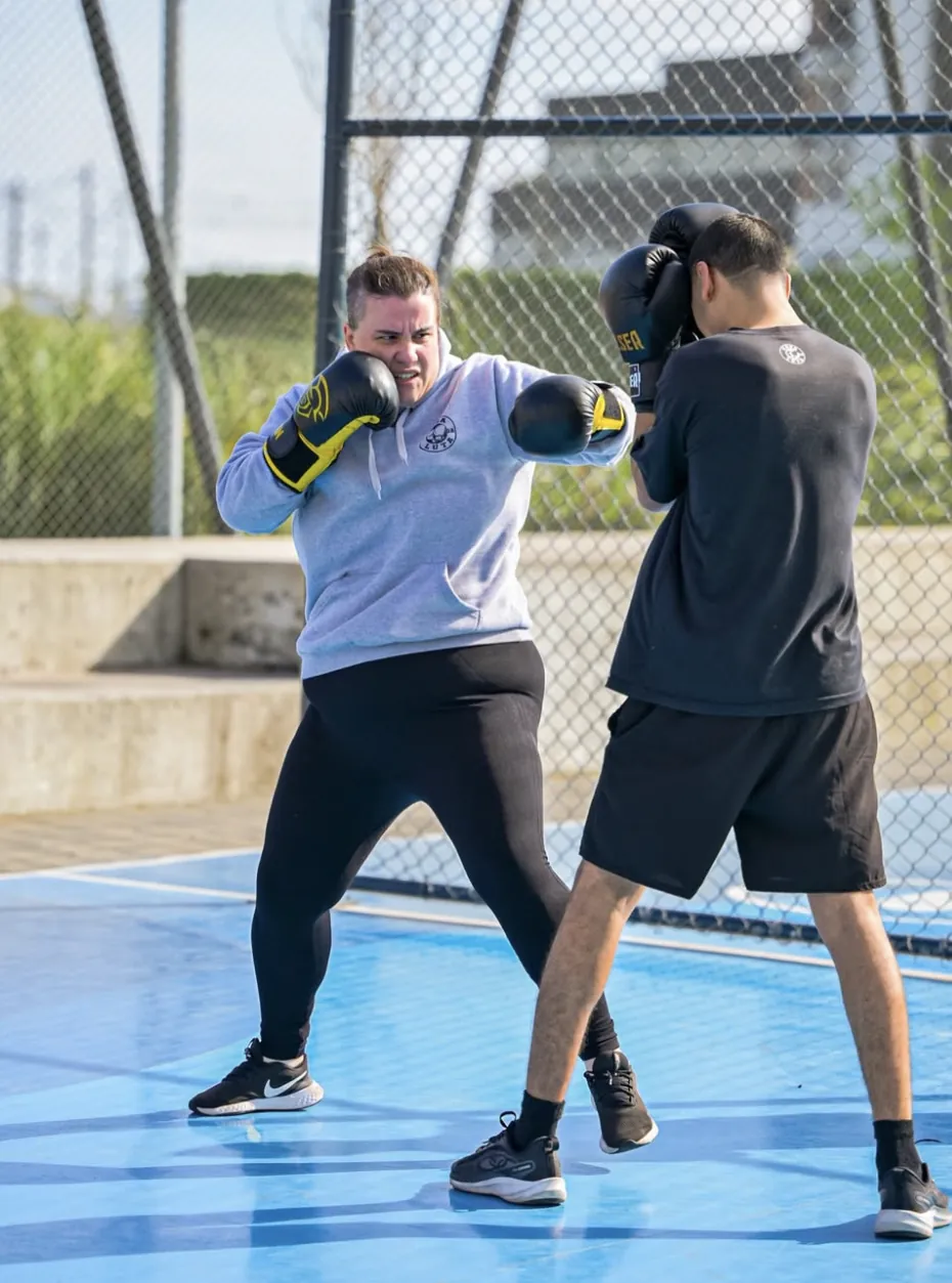 Aluna treinando boxe em dupla na quadra ao ar livre
