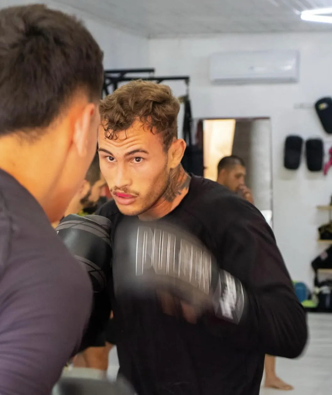 Lutador em guarda com luvas de boxe durante treino em dupla
