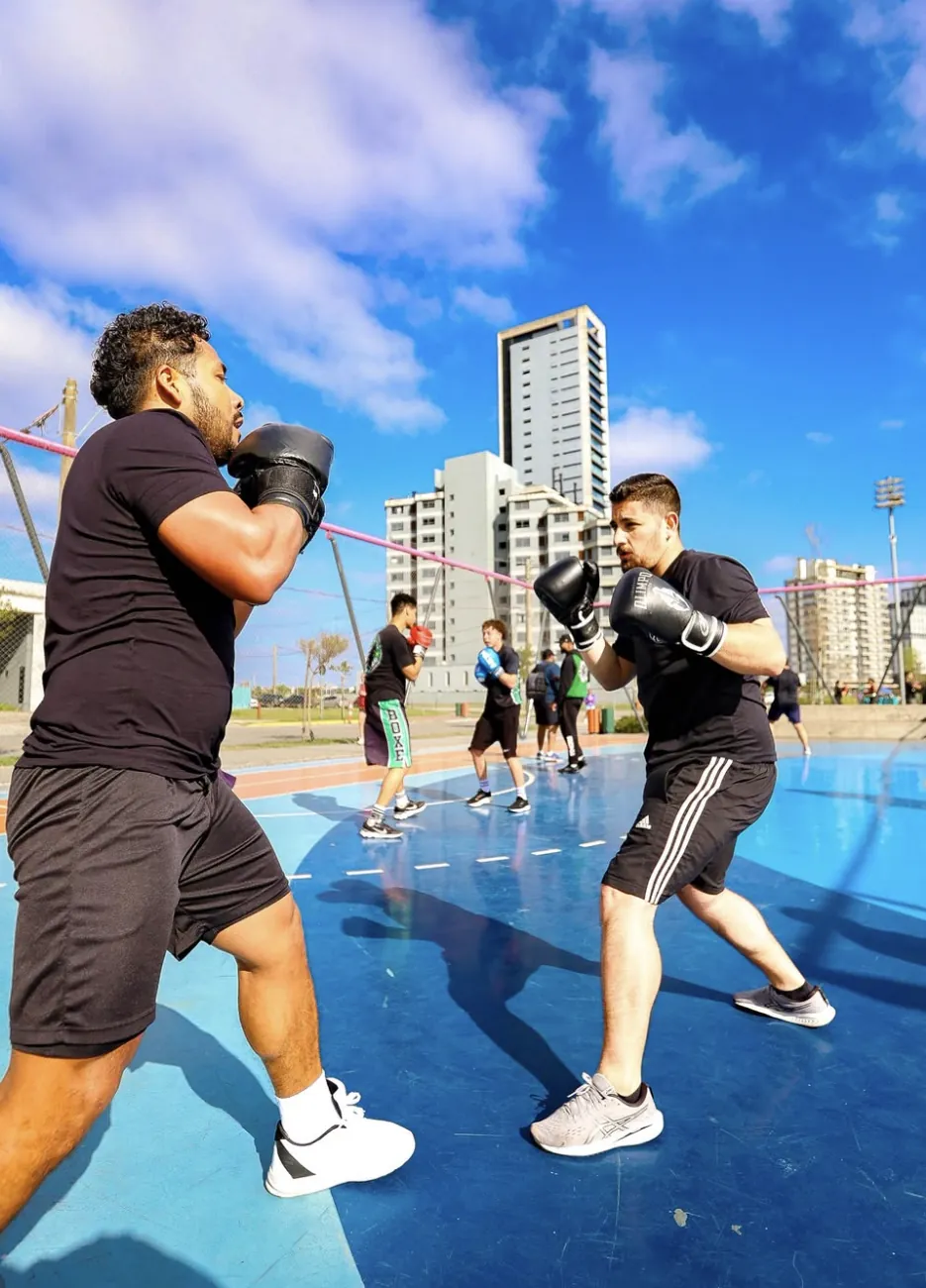 Treino em dupla ao ar livre, com a turma ao fundo